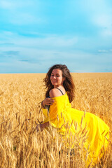 A young girl with long hair and a yellow robe fluttering in the wind is dancing in a wheat field