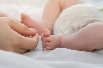Mother's hands near the little feet of her newborn baby. Mom and Child. A beautiful conceptual image of motherhood. Happy family concept. Copyspace
