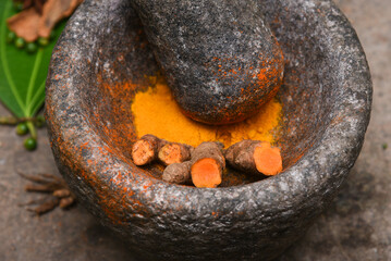 turmeric roots and powder in a mortar Kerala South India. Traditional Indian kitchen using vintage...