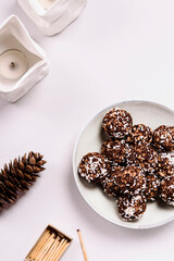 Swedish chocolate balls and cup of cocoa with marshmallow on grey concrete table. Cozy winter breakfast. Chokladbollar. Homemade healthy raw cocoa oatmeal balls sprinkled with coconut flakes