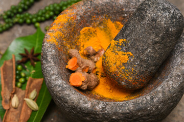 turmeric roots and powder in a mortar Kerala South India. Traditional Indian kitchen using vintage...
