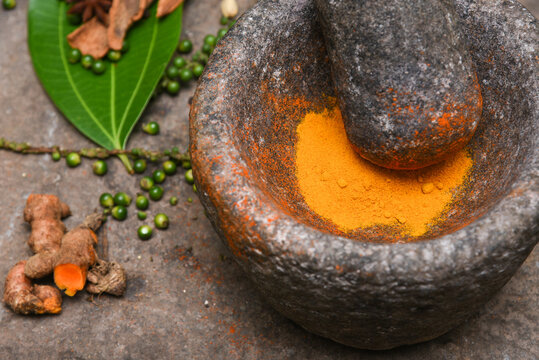 turmeric roots and powder in a mortar Kerala South India. Traditional Indian kitchen using vintage grinder for powdering spices which is used widely in curry and antiseptic Ayurveda treatments  