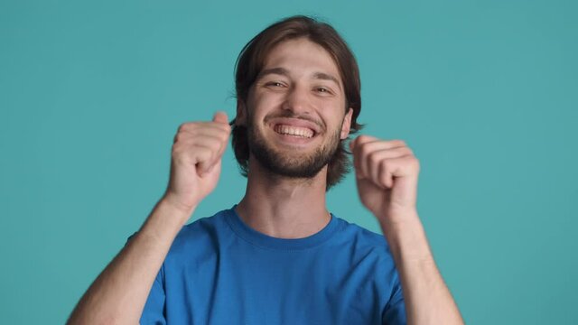 Handsome smiling brunette guy happily showing thumbs up gesture on camera over colorful background. Well done expression