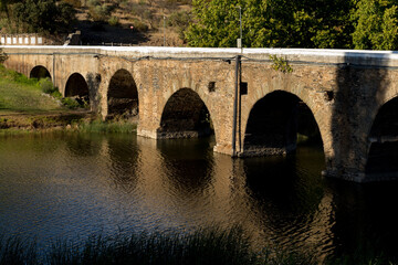 Fototapeta na wymiar Pillars of an old stone bridge over a riverbed in the summer. 