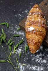One croissant lies on a rough cutting Board .