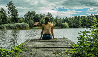 Girl sitting on a lake dock
