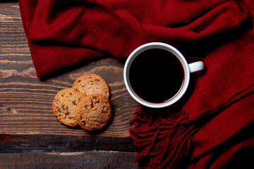 Cup of coffee and cookies with scarf on wooden table