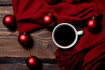 Cup of coffee with Christmas baubles and scarf on wooden table