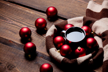 Cup of coffee with Christmas baubles and scarf on wooden table