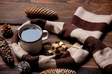 Cup of coffee and scarf on wooden table