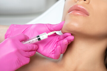 Cosmetologist makes lipolytic injections to burn fat on the chin, cheeks and neck of a woman...