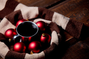 Cup of coffee with Christmas baubles and scarf on wooden table