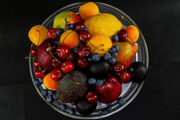 Still life of berries and fruit on a black background.
