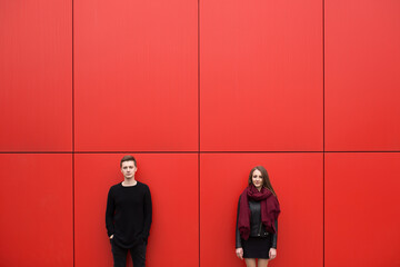 Young man and woman in passion, emotion, on the street with a backdrop of the red wall. Fashion