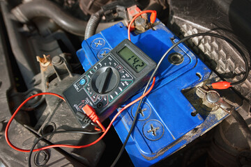 Multimeter with voltage range measurement to check up voltage level of the car battery. Measuring voltage on old car. Prepare car for autumn and winter. Voltmeter for service maintenance car battery