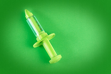 children's toy syringe on green background