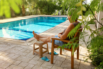 Old lady senior sitting in chair, relax next too pool in her house, happy seniour holidays, happy elderly lifestyle concept