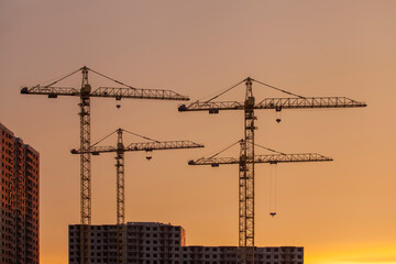 construction cranes against the background of bright evening clouds	
