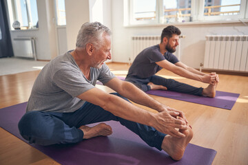 Beginner yogi and his coach practicing yoga