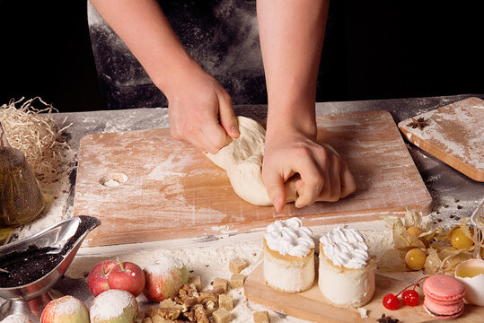 The dough is kneaded with your hands over a kitchen board on the table among the ingredients for cooking.