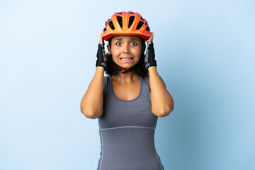 Young cyclist woman isolated on blue background doing nervous gesture