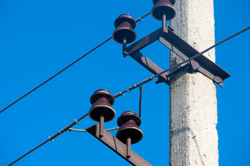 Closeup view of electric wires with electric insulator on a concrete pole - obrazy, fototapety, plakaty