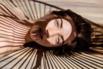 Young woman with shadows of palm leaf on her face.