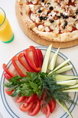 Pizza with olives and mushrooms and a plate of fresh vegetables