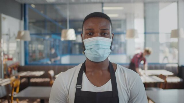 Portrait of afro-american waiter wearing protective mask looking at camera