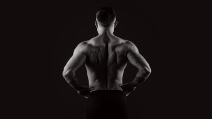 Fototapeta na wymiar Black and white bodybuilder view back on black background. Strongman.