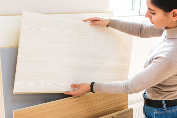 portrait of attractive woman in building store choosing wood laminate surface for home renovation...