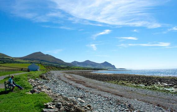 Seaside scene at the small village of Trefor in north Wales. Long, broad pebble beach with mountains in the distance.  Blue skies and copy space.