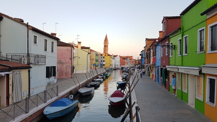 Fototapeta na wymiar Burano, with sunset, gondola, water view, river view and reflection, an island in the Venetian Lagoon, Venice, northern Italy, lace work and brightly coloured (colored) houses and homes