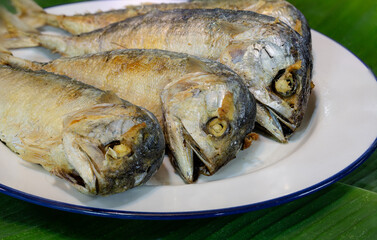 Fried steamed mackerel ripe, in white dish on green banana leaf