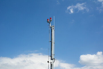 Obraz premium Aircraft warning light - light on the top of high an tall pole, post and mast. Blue sky as copy space.