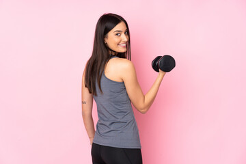 Young woman making weightlifting isolated on pink background