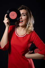 Fototapeta premium funny blonde girl with vinyl records in hands on a black background