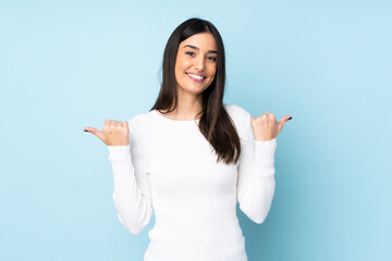 Young caucasian woman isolated on blue background with thumbs up gesture and smiling