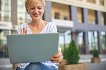Happy woman waving at a friend via Skype