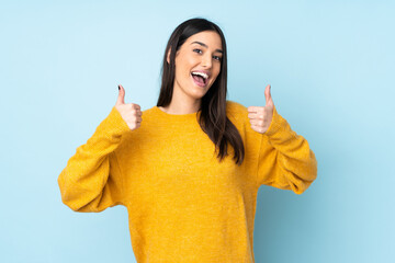 Young caucasian woman isolated on blue background giving a thumbs up gesture