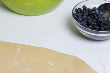 Ingredients for making dumplings stuffed with blueberries and cherries. Berries in containers, rolled out dough on the table.