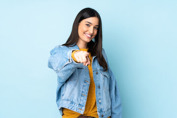 Young caucasian woman isolated on blue background pointing front with happy expression