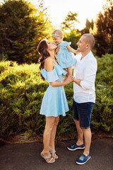 Naklejka na ściany i meble Loving overjoyed parents hold their adorable daughter