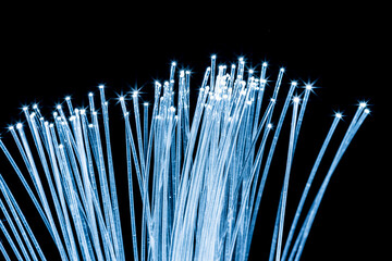 Bundle of optical fibers with blue light. Black background.