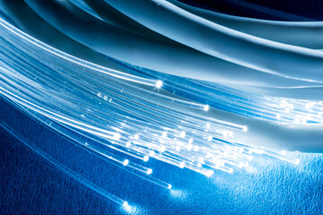 Network cables and optical fibers with light on blue background.