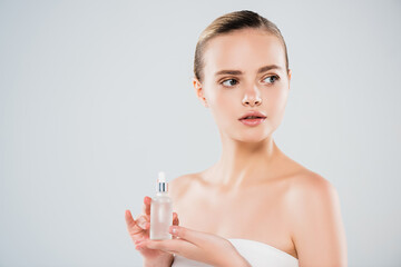 attractive young woman holding bottle with serum isolated on grey