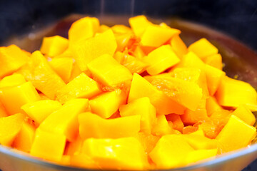 Pumpkin pieces in a deep transparent glass bowl. Chopped pumpkin (butternut squash) in salad dish