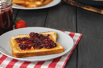 Toasted bread slices with berry jam on wooden table