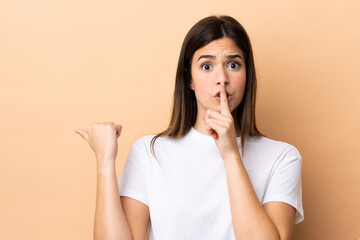 Teenager Brazilian girl over isolated background pointing to the side and doing silence gesture