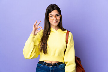 Teenager Brazilian student girl over isolated purple background showing an ok sign with fingers